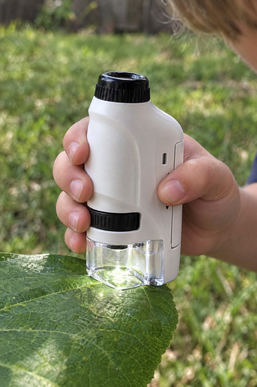 A child holds the Miniscope against a leaf in the garden
