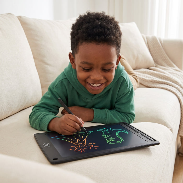 A smiling child lies on a sofa drawing a volcano and a green dinosaur on the tablet with its pen
