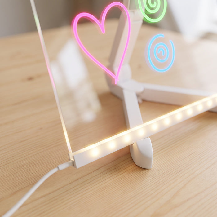 The glowing light bar along the bottom of the clear board up close, with the cable plugged in and a lit-up pink heart above.